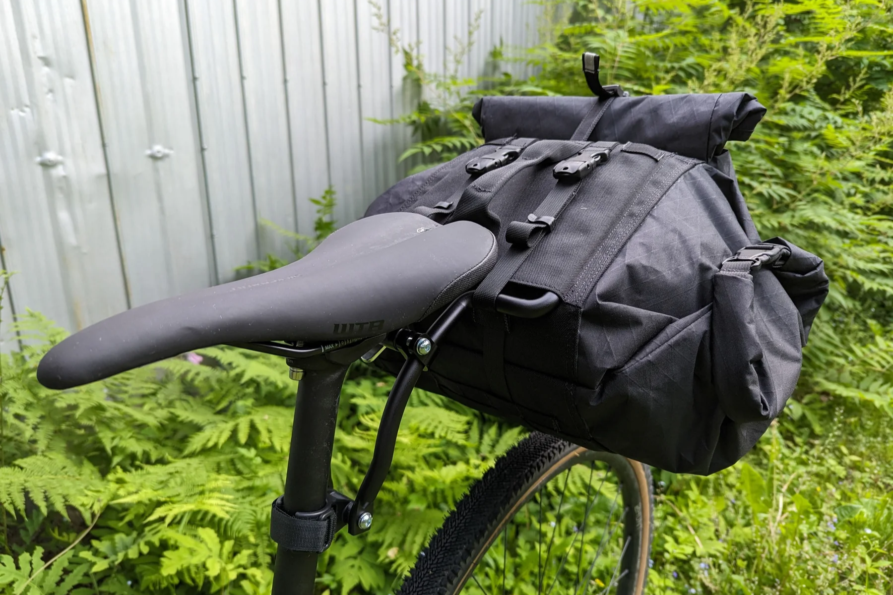 Black bike saddle bag attached to a bicycle with a green forest background